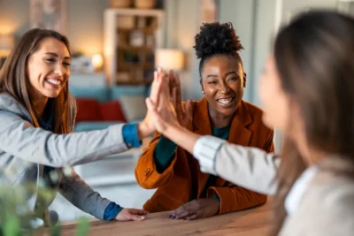 3 woman are engaged in a 3-way high-five-celebrating-goals-achieved
